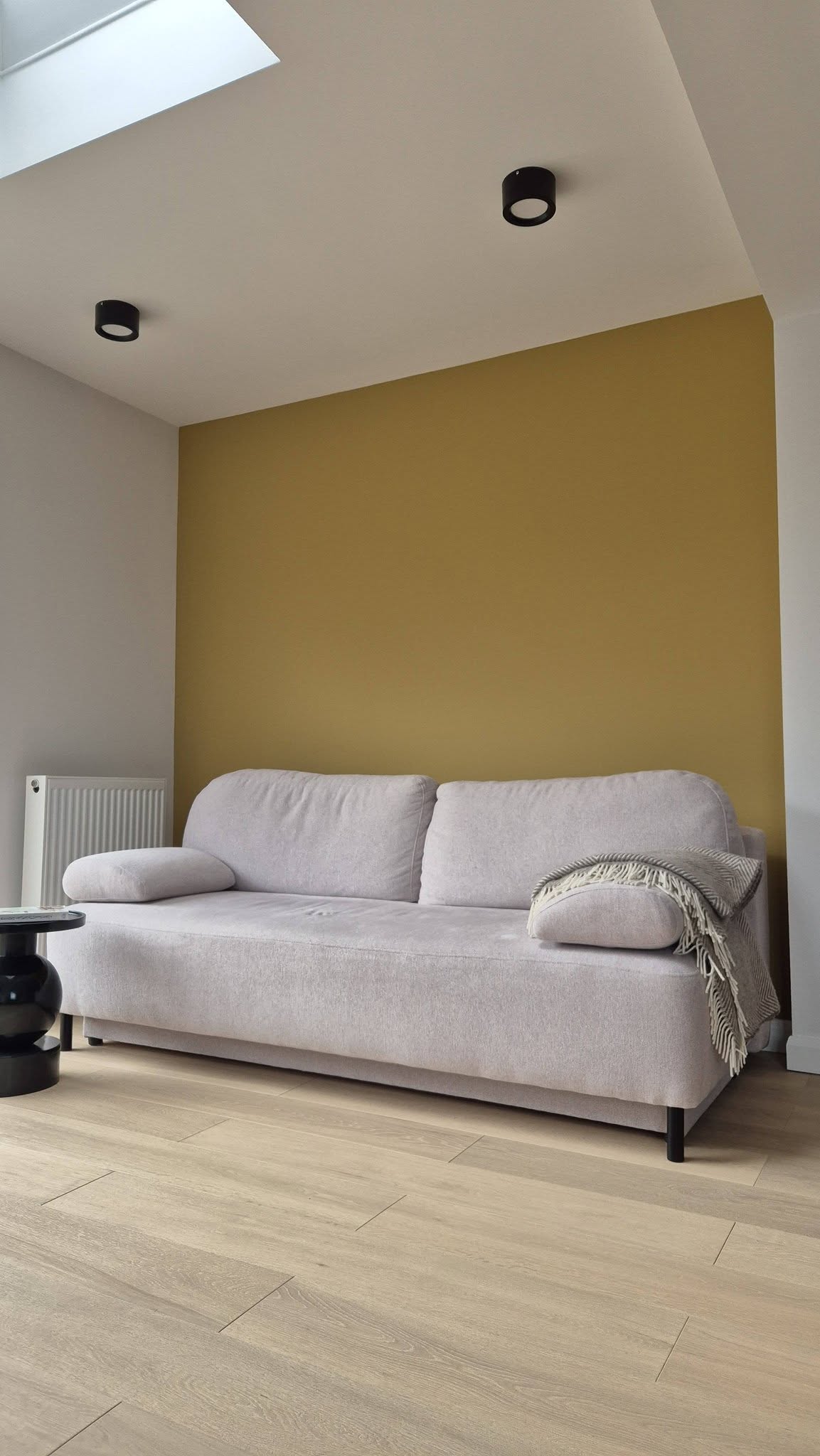 Living room with a mustard feature wall and pale walls