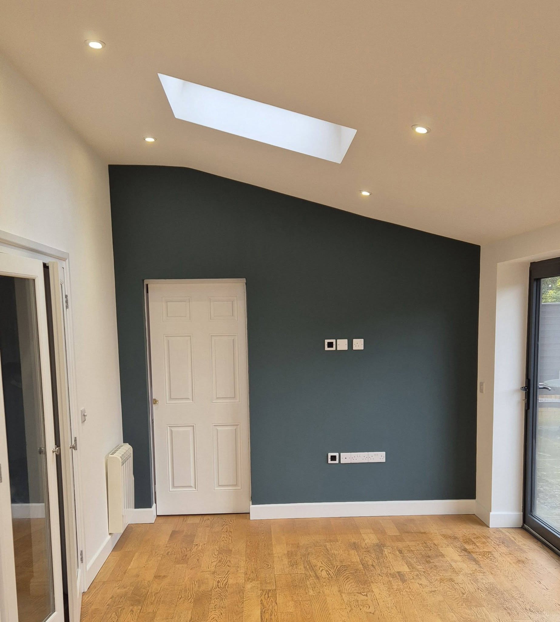 Garden room with a dark slate blue feature wall under a roof light