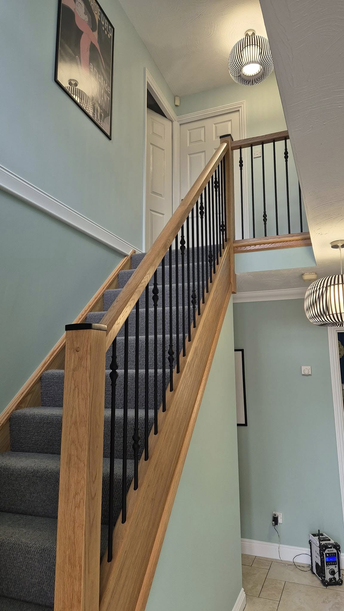Hallway and oak staircase painted in pale sage with a white dado rail