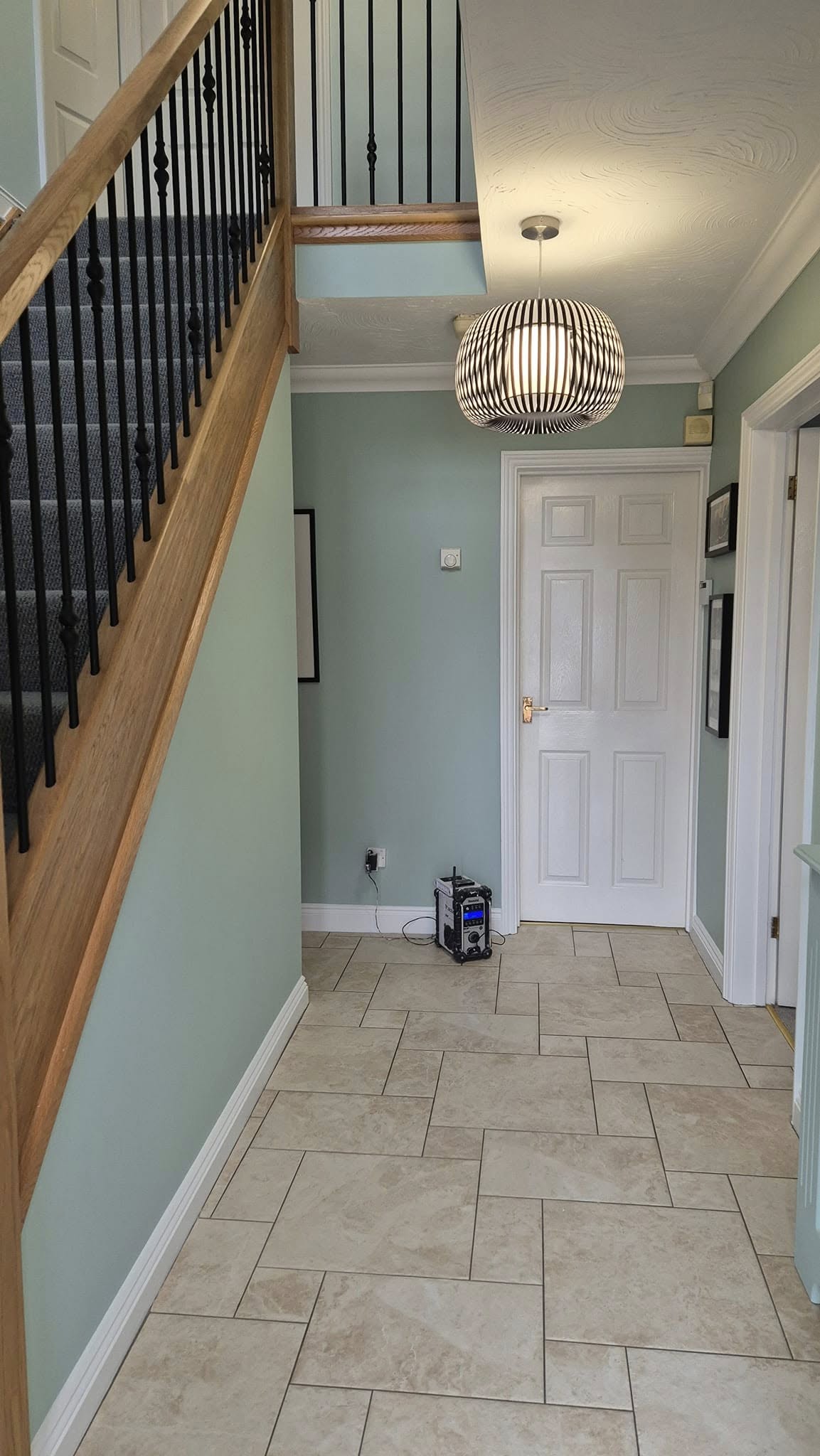 Sage green hallway with white doors and a stone tiled floor
