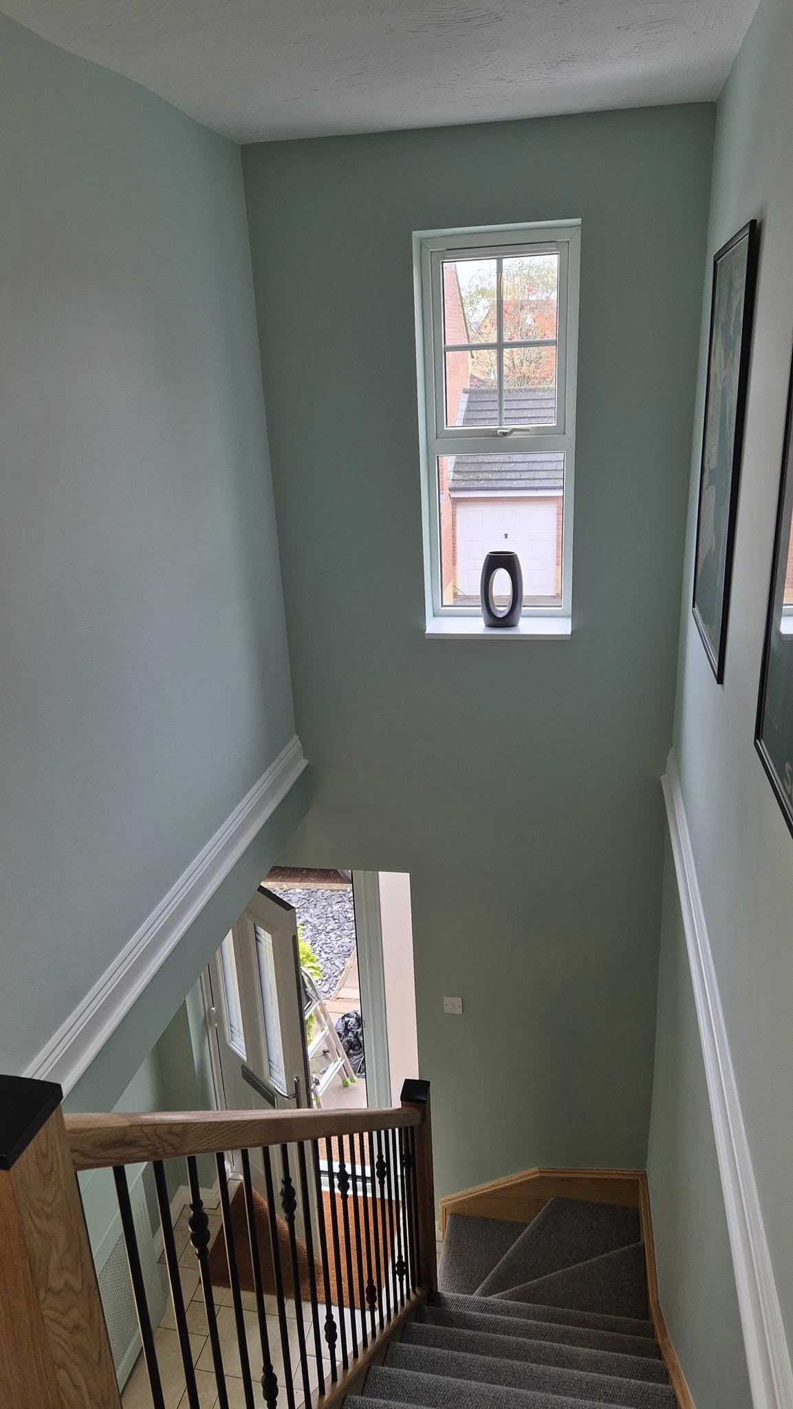 Stairwell painted sage green with a white dado rail and oak handrail