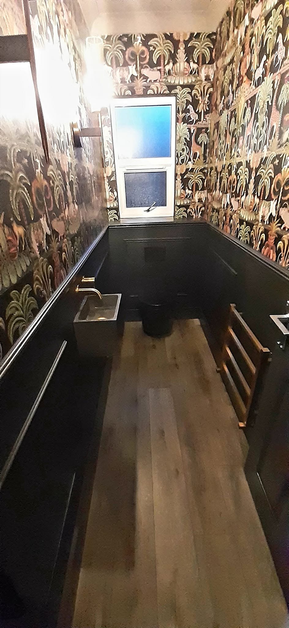 Cloakroom with black panelling and bold patterned wallpaper