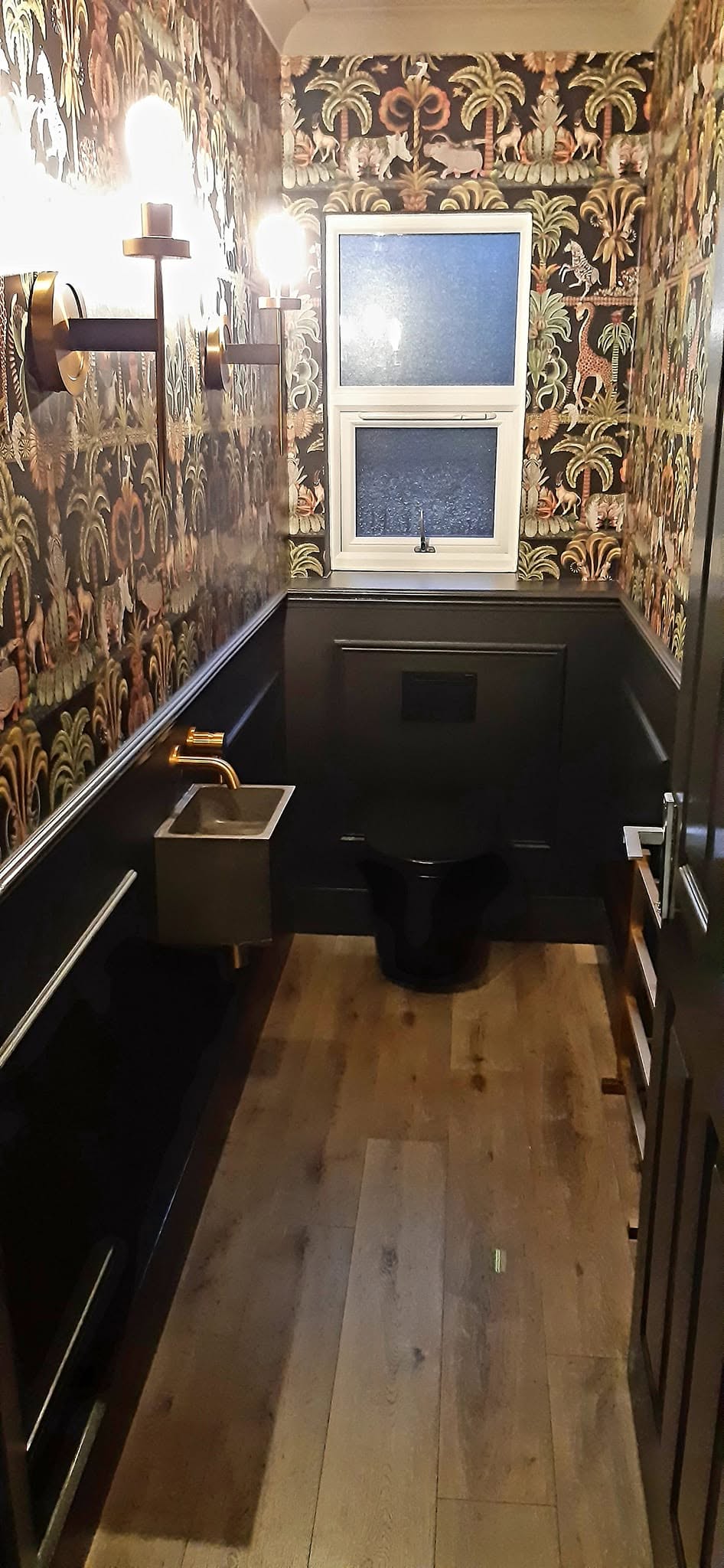 Cloakroom with black panelling below patterned wallpaper
