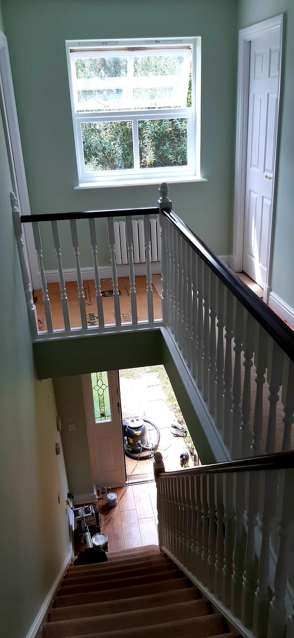 Stairwell from the landing with green walls and white spindles