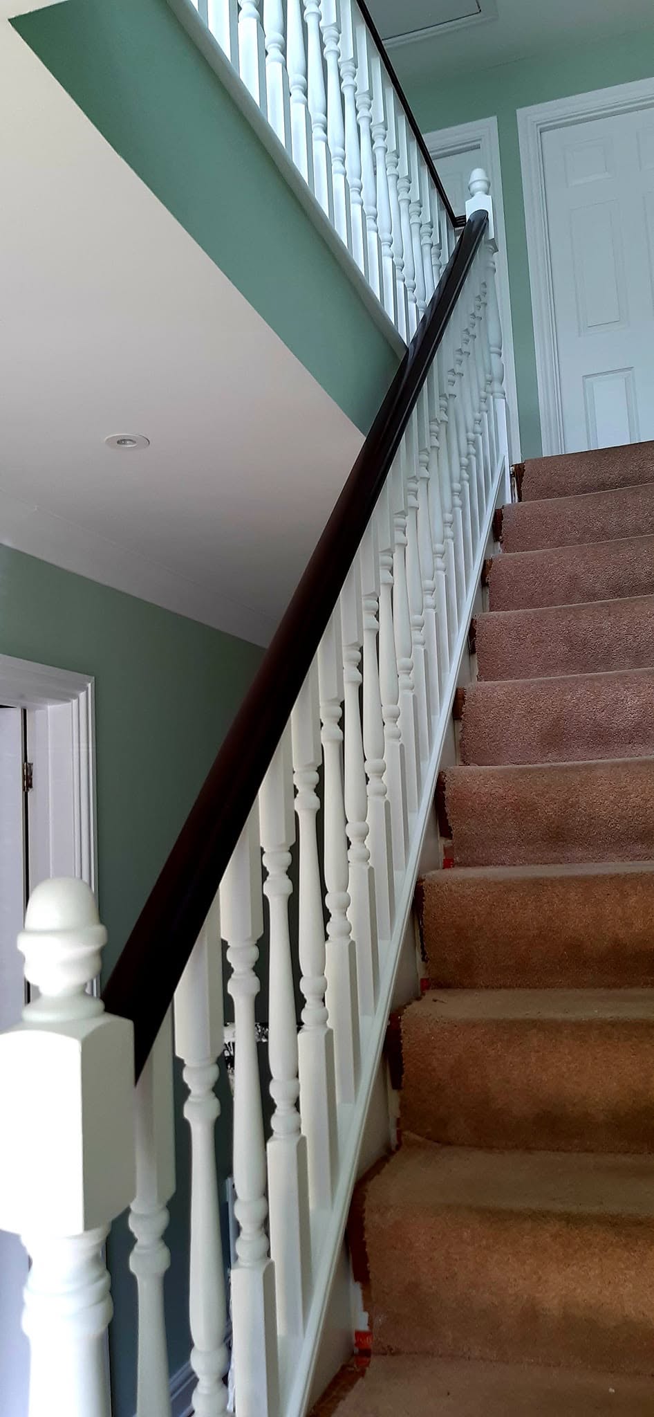 Staircase with a white balustrade and dark handrail