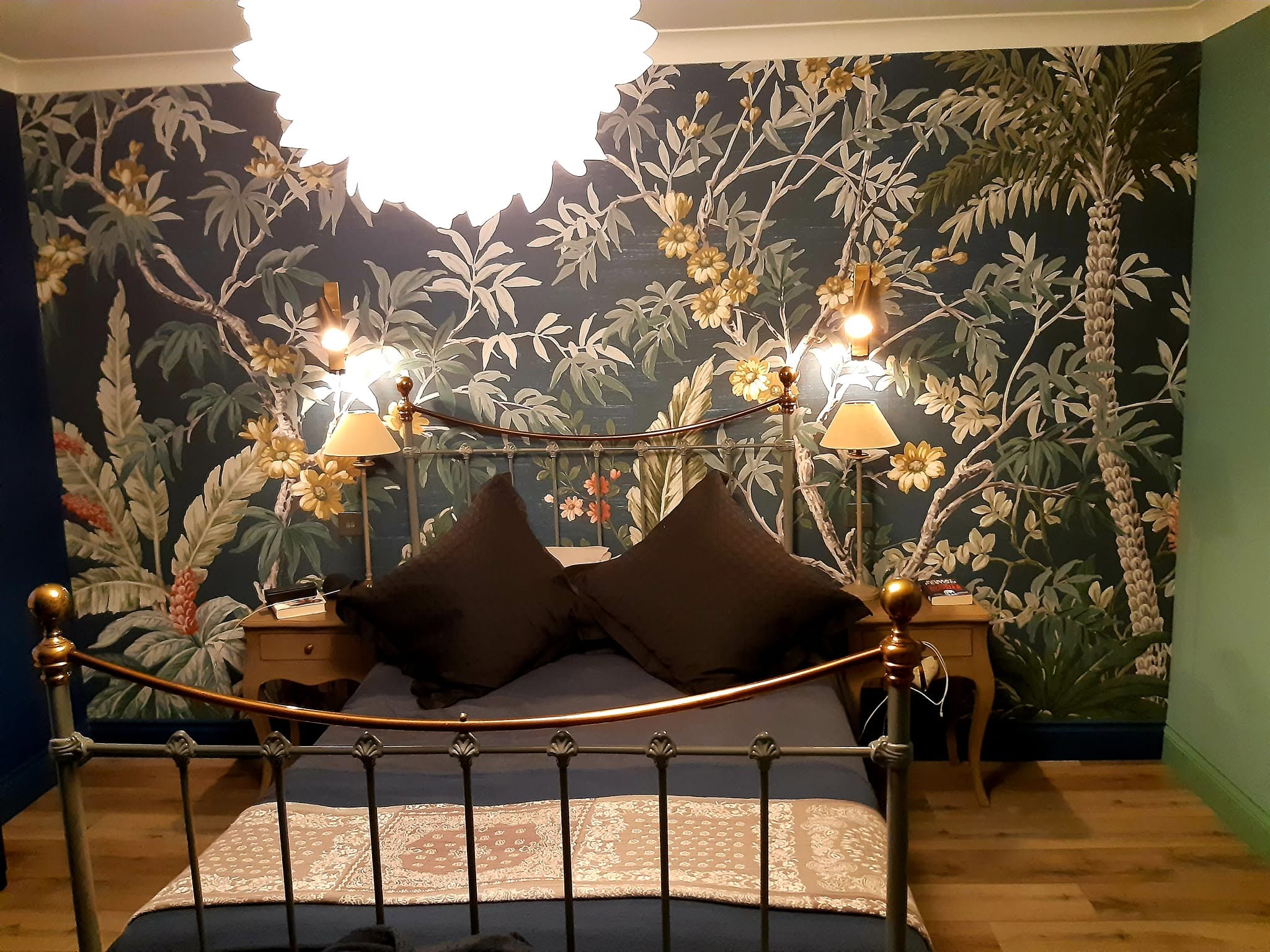 Bedroom with a full wall tropical palm mural behind a brass bed