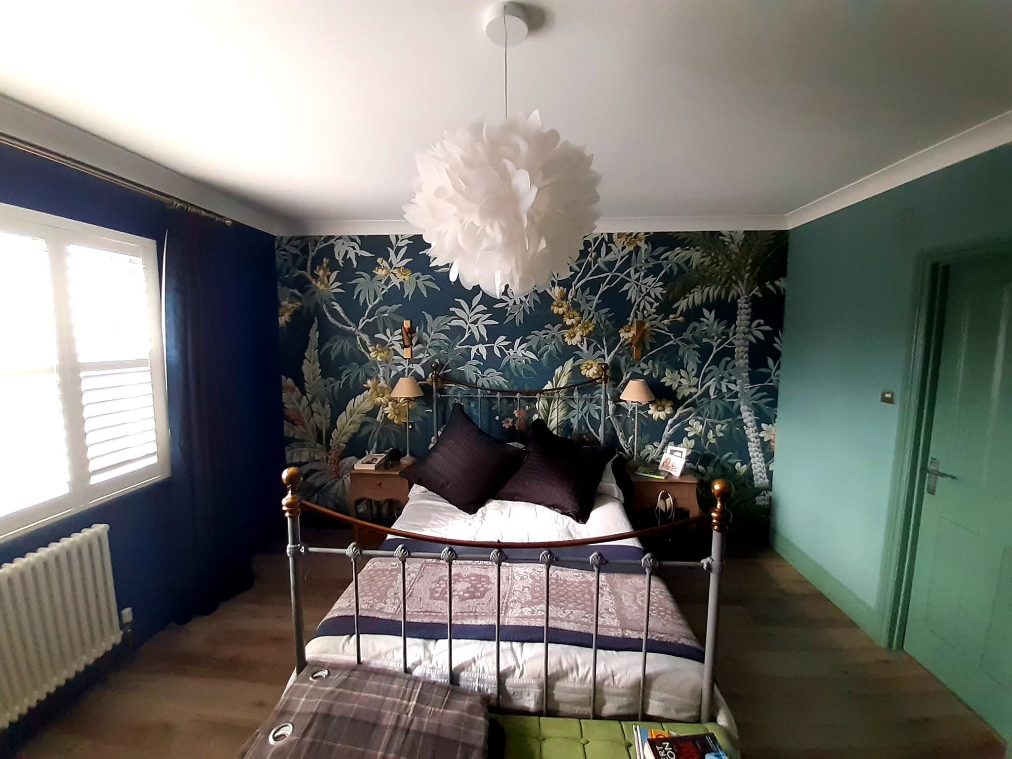 Bedroom with a navy wall beside a tropical palm mural