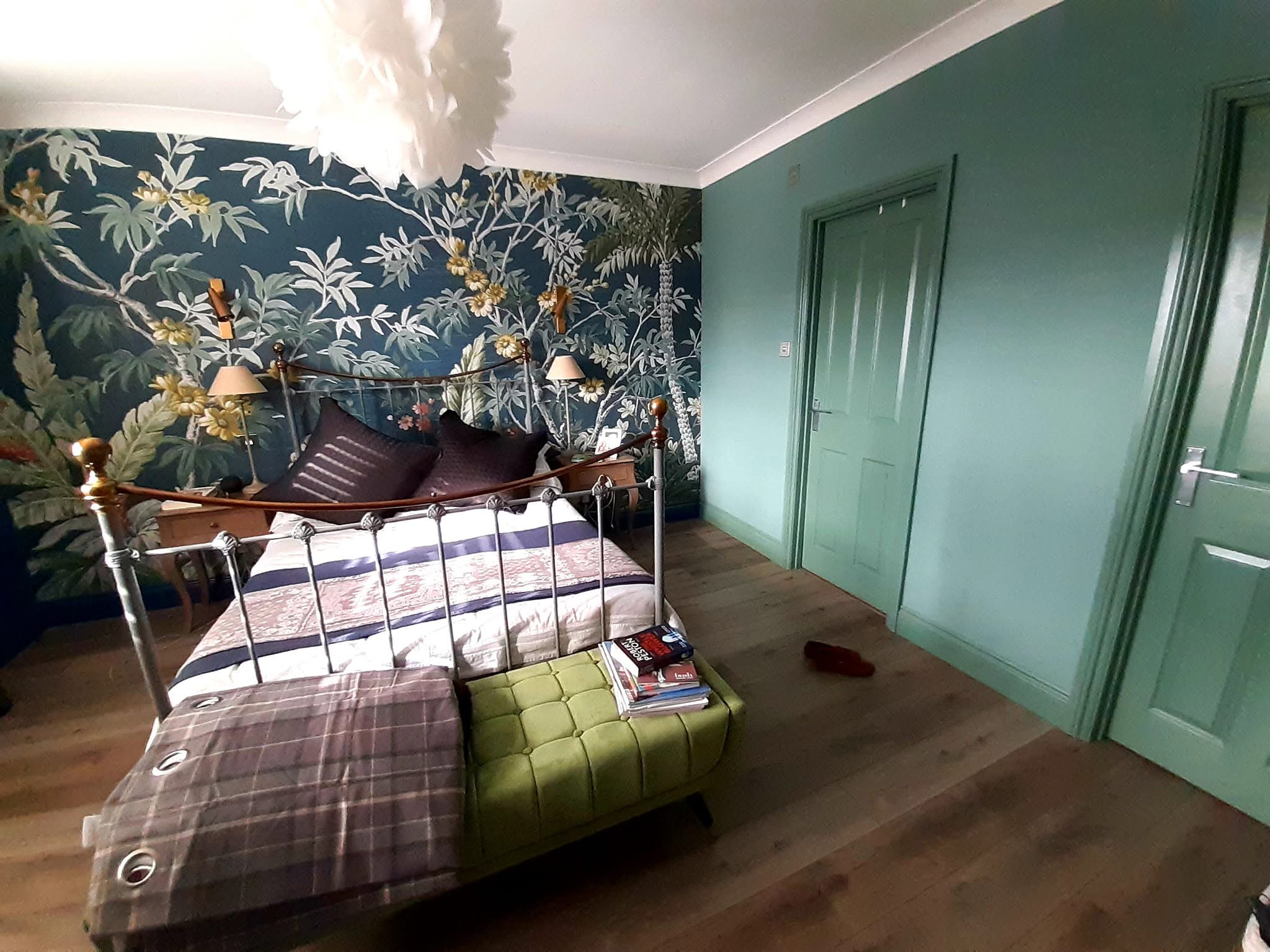 Bedroom with palm mural wallpaper and a green painted door