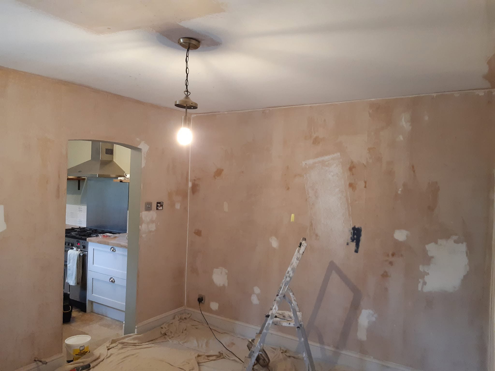 Before: patched pink plaster walls around an arched opening to the kitchen