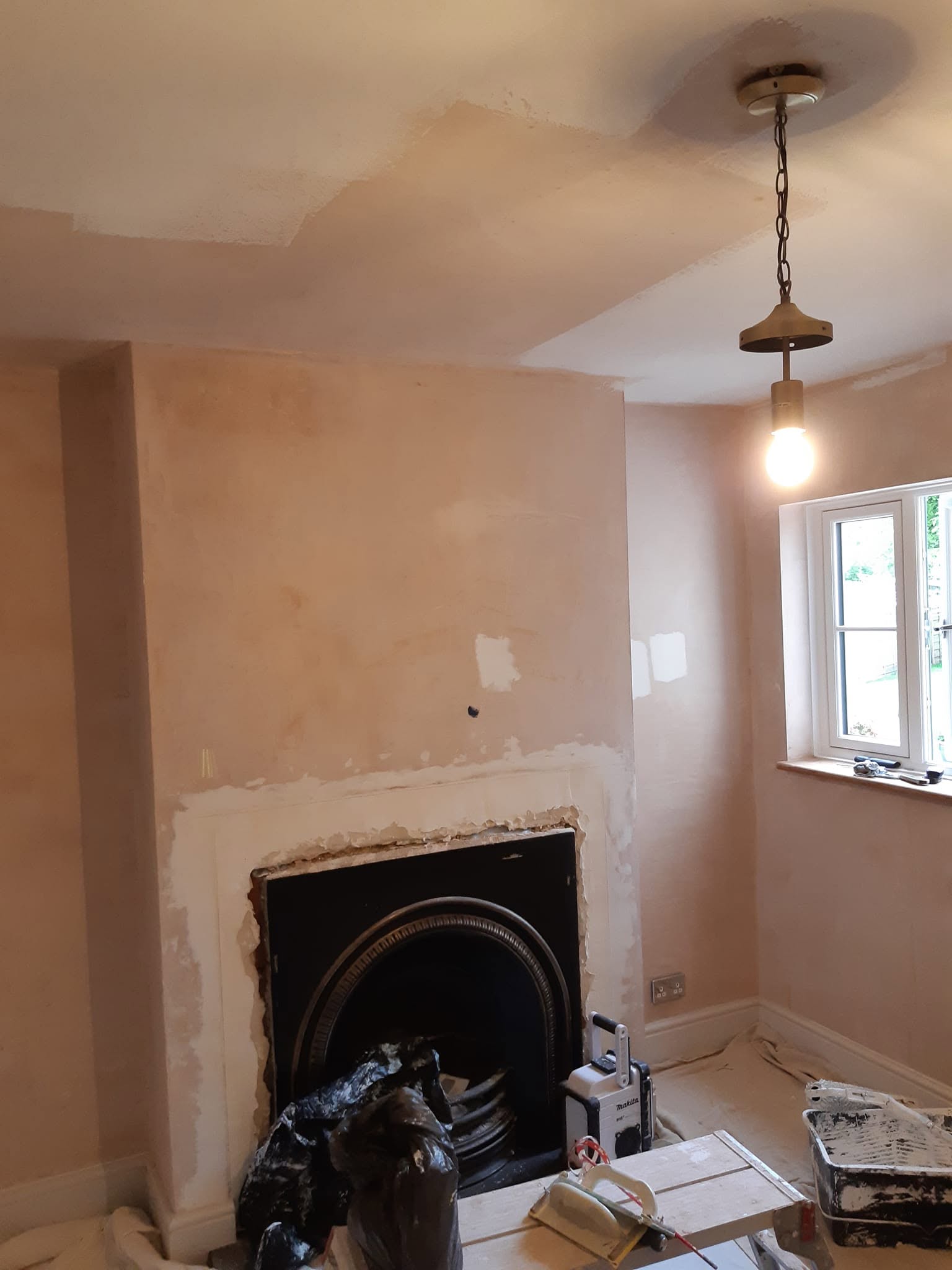 Before: bare plaster around a cast iron fireplace