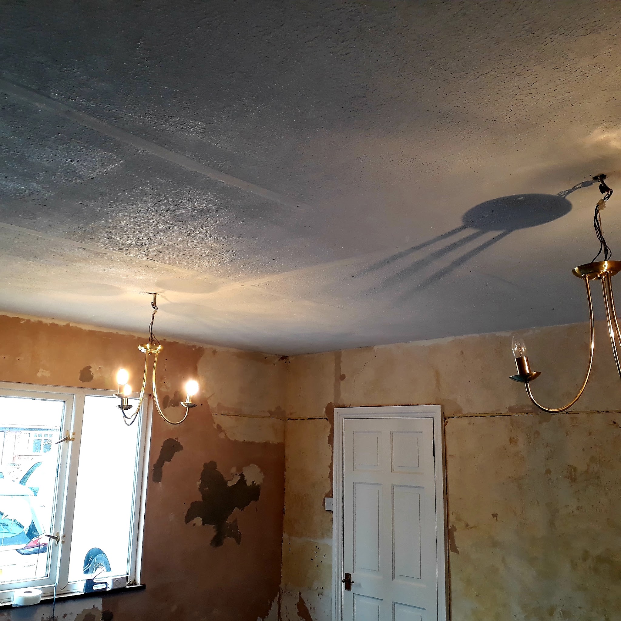 A room stripped back with old plaster showing and a textured ceiling