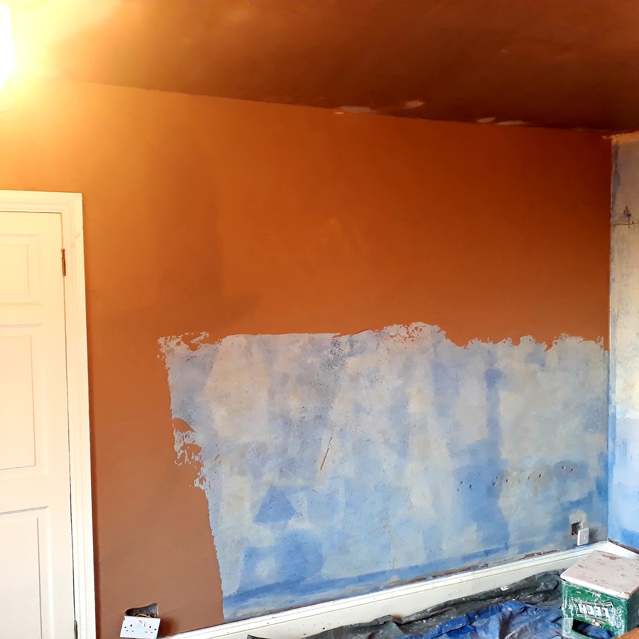 An orange wall part way through being repaired and repainted