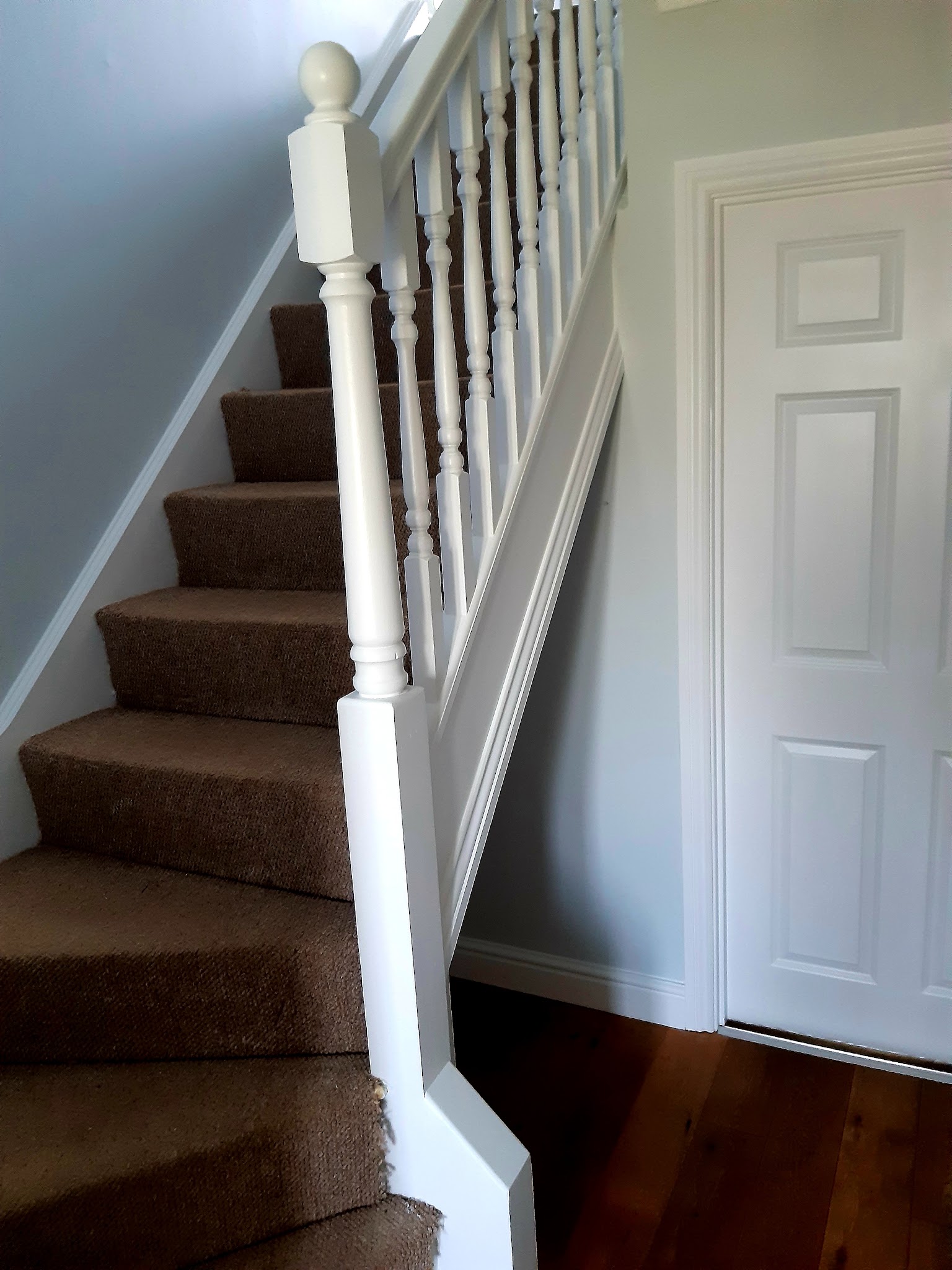 White painted staircase spindles and newel post beside a panelled door